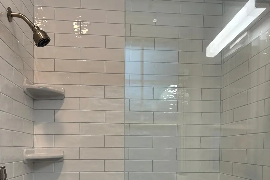 Walk-in shower with white subway tile, glass panel and teak bench