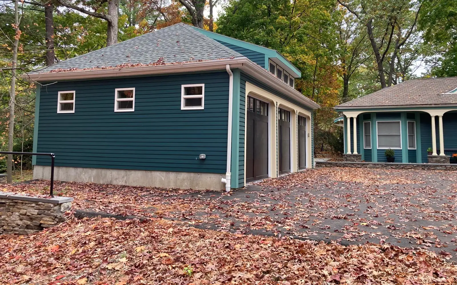 Three-car garage with teal siding, built to match the house