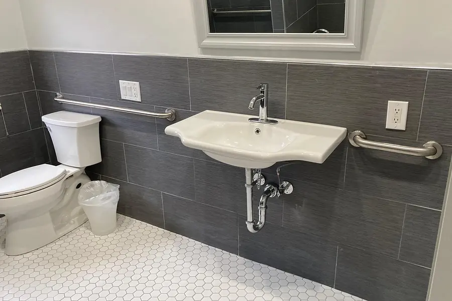 Bathroom with gray plank wall tile, white hexagon floor tile and grab bars